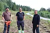Tre mann i en skråning med en vei i bakgrunnen.